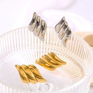 Elegant gold and silver angel wing texture earrings displayed in a glass bowl