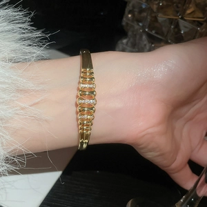 Close-up of 18k gold plated bangle with wavy zircon rows worn on a model wrist