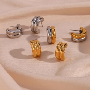 Detail of C-shaped double hoop earrings in gold and silver finish on silk fabric