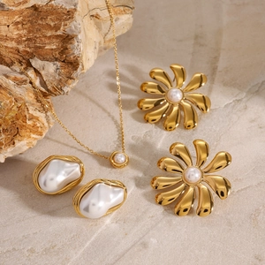 Elegant gold pearl jewelry set with floral earrings on natural stone background
