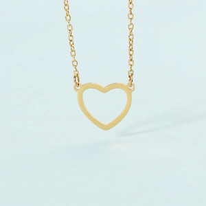 Close-up of minimalist gold hollow heart pendant on a delicate chain over blue background