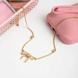 Gold stainless steel bow necklace with diamond heart pendant and heart accents on the chain