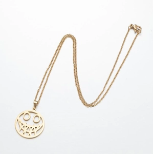Close-up of golden stainless steel necklace with round hollow smiley face skull pendant