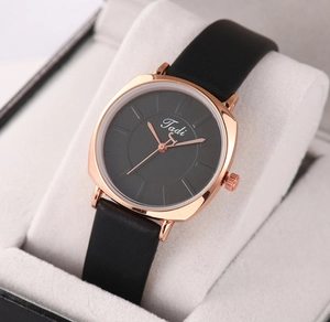 Detail of square gold case with black dial and leather strap on display cushion