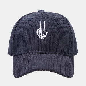 Close-up of white skeleton hand embroidery on dark blue corduroy baseball cap texture