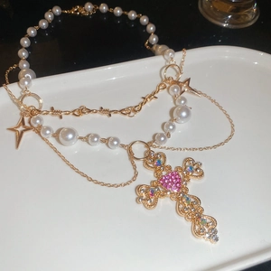 Detail of baroque pearl layered necklace with gold cross and pink heart gemstone