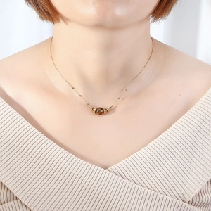 Minimalist gold tiger eye stone necklace worn by a model on a beige sweater
