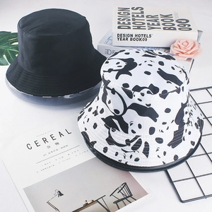 Flat lay of black and panda print cotton bucket hats with books and flowers on white background