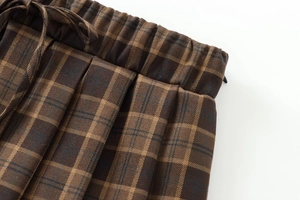 Close-up of brown plaid mini skirt featuring elastic waist and matching drawstring detail