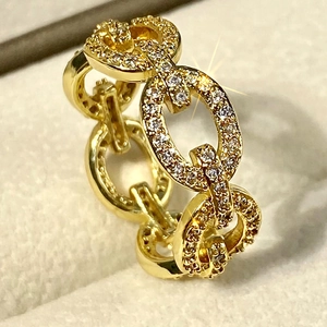 Macro detail of a golden chain link ring encrusted with micro-pave white zirconias