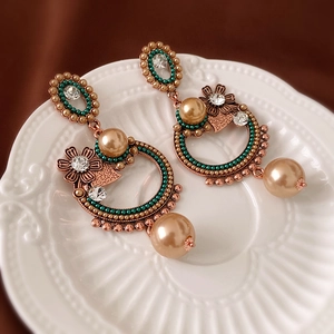 Détail de boucles d'oreilles vintage avec perles champagne et perles vertes sur céramique