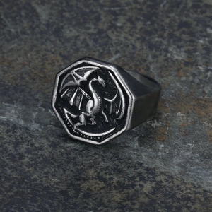 Macro shot of silver dragon relief on octagonal stainless steel ring over dark stone