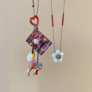 Detail of handmade resin cat pendant and floral pearl necklace with red heart clasp