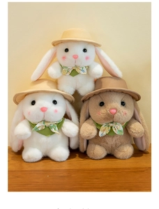 Detailed view of three plush rabbits with floral scarves and hats in cozy setting
