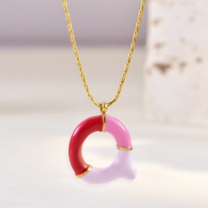 Close-up of letter Q pendant with pink, purple and red enamel on a gold chain