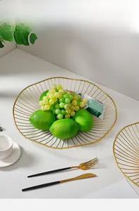 Detail of wave-edged gold iron fruit basket with lemons on a modern white table