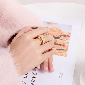 Detail of gold-plated wide band ring with four rows of sparkling white zircons on hand
