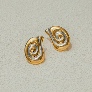 Orecchini a spirale oro e argento con finitura lucida a specchio su sfondo in pietra