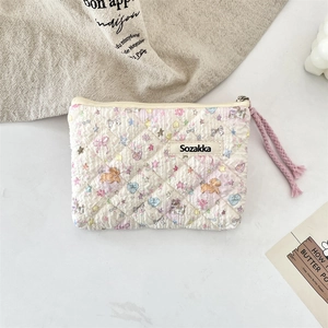 Quilted floral makeup bag with dog patterns and a pink braided dual zipper pull