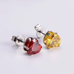 Close-up of red and yellow zircon heart stud earrings with metallic setting details