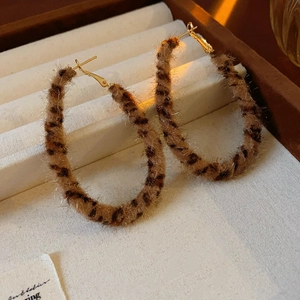 Close-up of leopard print velvet hoop earrings with golden needles on a jewelry tray