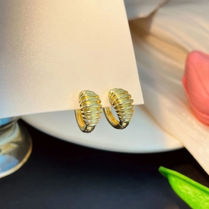 Gros plan détaillé de boucles d'oreilles créoles dorées à texture spirale