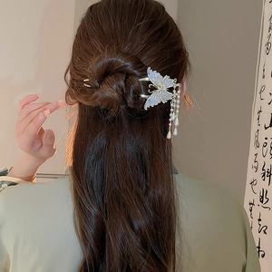 Nahaufnahme einer goldenen Schmetterlings-Haarnadel mit Perlen und Quasten auf dem Haar
