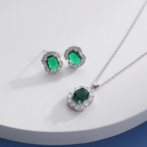 Macro detail of silver necklace and earrings with oval green gemstone and cubic zirconia