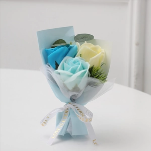 Detailed soap flower bouquet with blue roses and eucalyptus leaves in paper wrapping