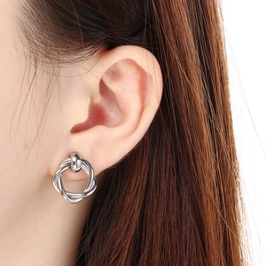 Close-up of silver knot earrings worn by a model showcasing the intricate metal design