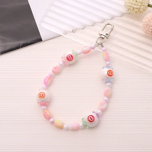 Pastel beaded phone charm with red numbers and silver lobster clasp on a textured surface