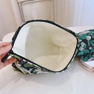Internal view of dark green floral cosmetic bag showing cream canvas lining and zipper