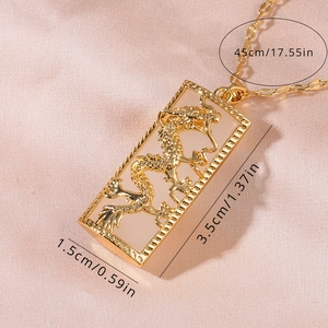 Macro shot of gold-plated dragon pendant necklace showing dimensions on silk background