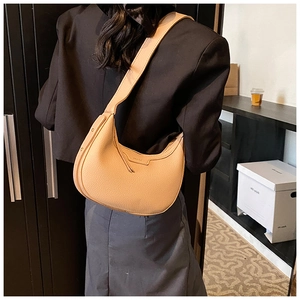 Dettaglio della borsa hobo a mezzaluna in pelle beige con trama litchi e tracolla