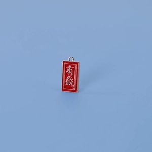 Gros plan sur un pendentif porte-bonheur en émail rouge et or avec caractères chinois