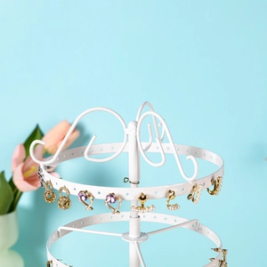 Detail of white multi-layer rotating earring organizer featuring heart hooks and round base