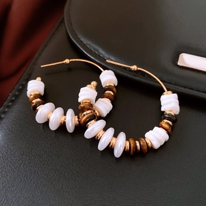 Détail de boucles d'oreilles créoles plaquées or 18 carats avec perles œil de tigre