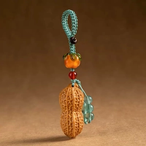 Detail of handcrafted rosewood persimmon and peanut keychain charm with woven cord
