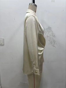 Détail d'une chemise en satin champagne montrant des plis élégants et une taille froncée