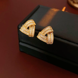 Gros plan de boucles d'oreilles triangles dorées avec micro-pavage de zircons scintillants