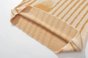 Vista dettagliata dell'orlo in maglia a righe con cuciture raffinate in beige e giallo