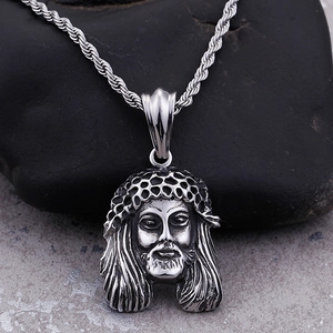 Macro shot of silver Jesus head pendant on a natural stone background with twisted chain
