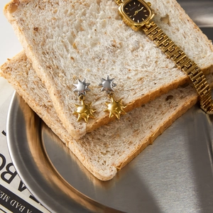 Detail shot of bicolor star earrings and gold watch displayed on creative food props