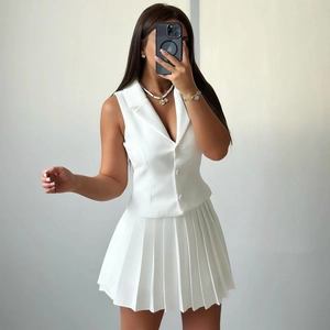 Détail d'un ensemble gilet de costume sans manches et mini-jupe plissée blanche