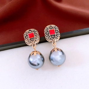 Detailed view of vintage gold earrings with red stones, black gems, and gray pearl drops