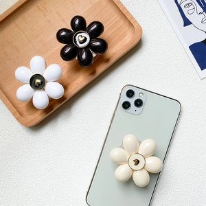 Detailed view of floral phone socket grip with gold heart on white wood tray