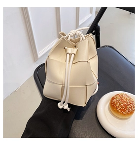 Detail of beige woven texture bucket bag with drawstring closure on a chair