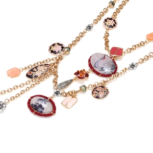 Detailed close-up of vintage golden necklace with crane motif and enamel flower charms