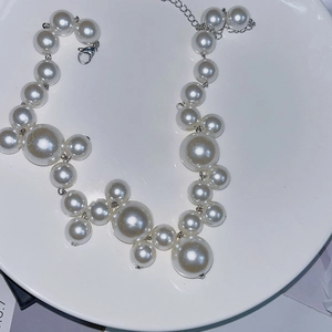Close-up of pearl necklace featuring multi-size clustered white pearls and silver lobster clasp