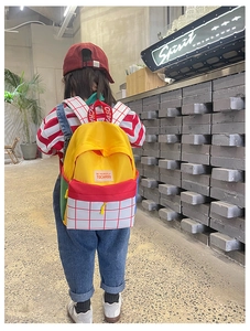 Kid wearing colorful color-block canvas backpack with Tochaso logo in cozy indoor setting